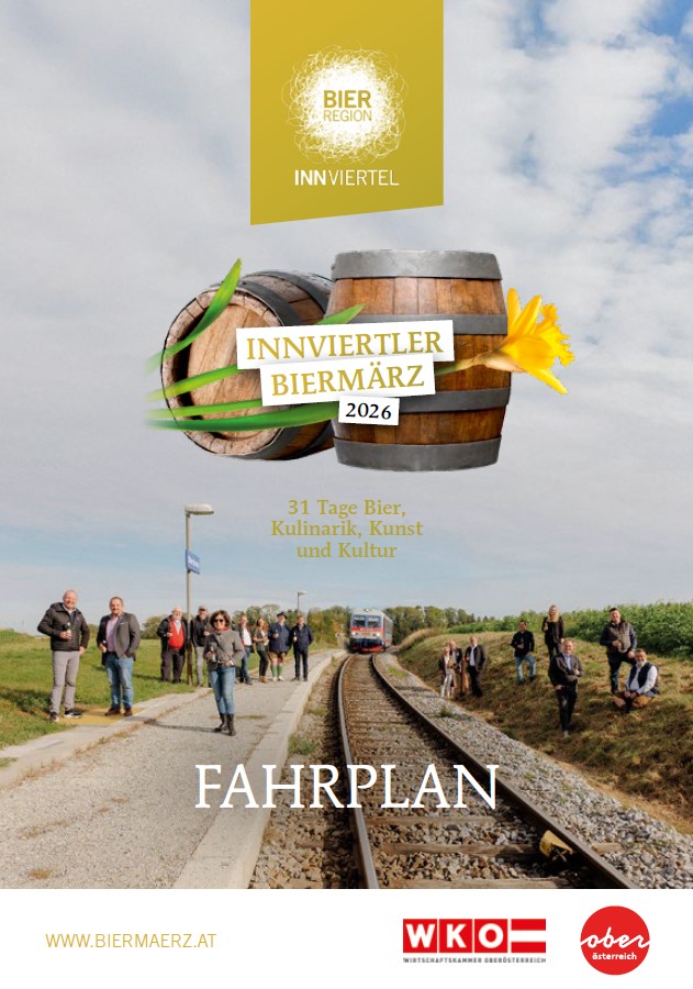 Einige Personen stehen links und rechts von einem Bahngleis. Ein Zug ist in der Ferne zu sehen.