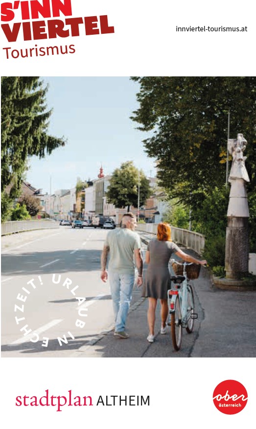 Das Titelbild zeigt einen Mann und eine Frau von hinten, die über eine Brücke in Richtung Stadt gehen. Die Frau trägt ein Kleid und schiebt ein Fahrrad. Aufschrift: Stadtplan Altheim